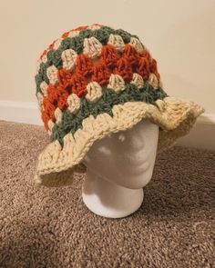 a white mannequin head wearing a multicolored crocheted sun hat