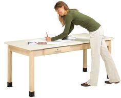 a woman standing at a desk writing on a piece of paper