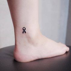 a small black ribbon tattoo on the ankle