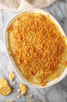 a casserole dish filled with cheese and crackers on a marble counter top