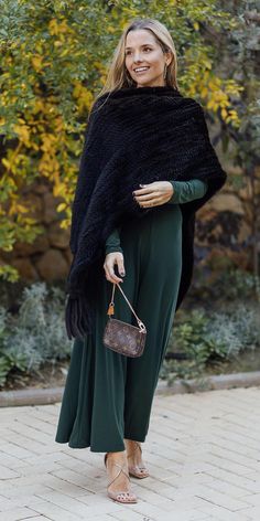 a woman wearing a black shawl and green pants