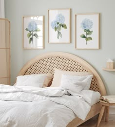 a bed with white linens and blue flowers on the wall above it in a bedroom