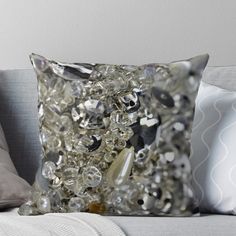 a close up of a pillow on a couch with some beads in the back ground