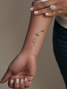 a woman's arm with a bird tattoo on the left side of her wrist