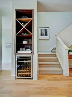 an empty wine cellar in the middle of a room with stairs leading up to it