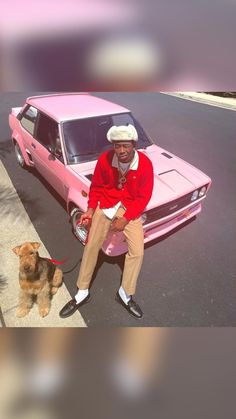 a man sitting on top of a pink car next to a dog