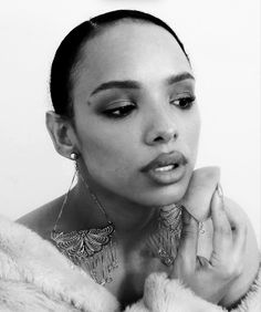 a black and white photo of a woman with earrings on her head, looking at the camera