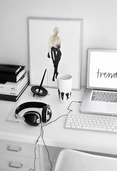 a laptop computer sitting on top of a desk next to a cup and headphones