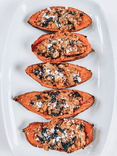 four baked sweet potatoes on a white plate topped with blue cheese and other toppings