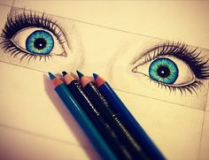 two pencils are laying next to each other on a sheet of paper with an eye drawn