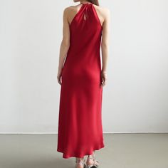 Introducing our exquisite Scarlet Halter Dress. Crafted from luxurious satin in a mesmerizing shade of deep red, this dress is a celebration of opulence and style. The halter neckline gracefully accentuates the shoulders, while the front neck flower, adorned with meticulously placed crystals, adds a touch of celestial brilliance.  Designed to make a statement at any special occasion, the Scarlet Elegance dress drapes elegantly, flattering the silhouette with its tailored fit. The flowing skirt a