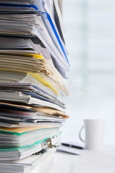 a stack of papers sitting on top of a desk next to a cup