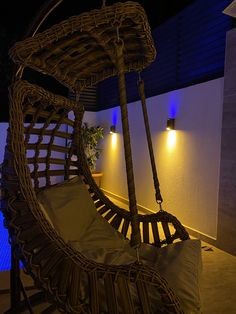 a wicker hammock hanging from the side of a building with lights on