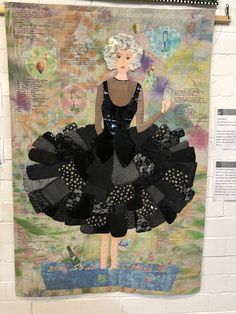 a woman in a black dress is hanging on a wall