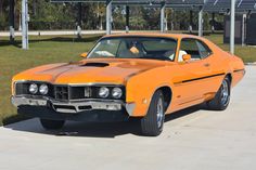 an orange muscle car parked in front of a building