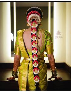 a woman in a yellow sari with a red and white garland on her head