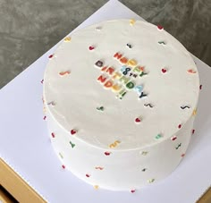 a white cake with the words happy on it sitting on top of a cardboard box