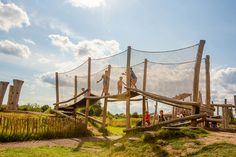 children are playing on a wooden bridge in the grass with netted netting over it