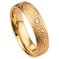 a gold wedding ring with a diamond in the center and an engraved pattern on it