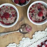 three bowls filled with oatmeal and berries on top of a wooden table