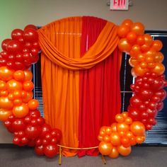 an orange and red backdrop with balloons in the shape of a circle on top of it