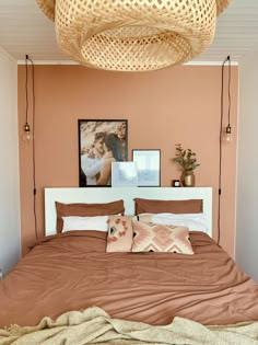 a bed with two pillows on top of it and pictures hanging above the headboard