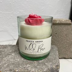 a candle with a red rose in it sitting on a rock