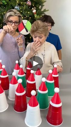 two women standing next to each other in front of a table filled with red and white cones