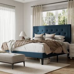 a bedroom with a large bed and blue headboard on the side, along with a footstool