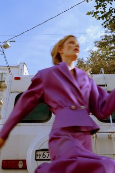 a woman in a purple dress is standing next to a white truck and some wires