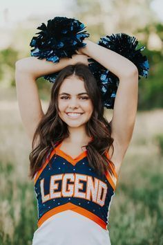 a girl in a cheerleader uniform holding her hands up to her head and smiling at the camera