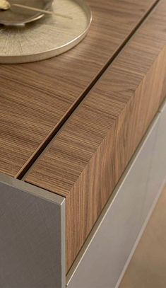 a close up of a clock on top of a wooden table with silver trimmings