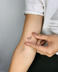 a woman's arm with a butterfly tattoo on the left side of her hand