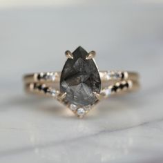 an engagement ring with a pear shaped gray diamond