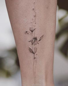 a small flower tattoo on the side of a woman's leg, with flowers coming out of it