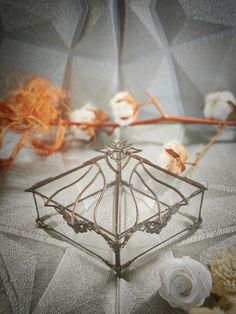 a wire basket with flowers and cotton in front of it on top of a table