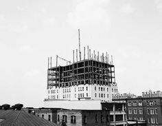 a building under construction with scaffolding on top and buildings in the foreground