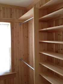 an empty room with wooden shelves and open window in the corner on the right side