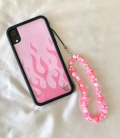 a pink phone case sitting on top of a white bed next to a lanyard