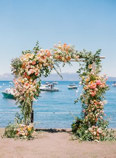 an outdoor wedding ceremony setup with flowers and greenery on the side of the water