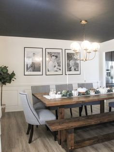 a dining room table and bench with pictures on the wall