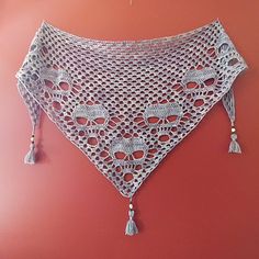 a crocheted shawl with tassels hanging on a wall