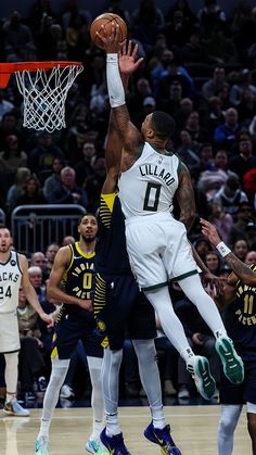 the basketball player is trying to dunk the ball into the hoop while other players look on