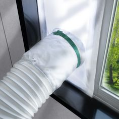 an air conditioner sitting in front of a window next to a green tree outside