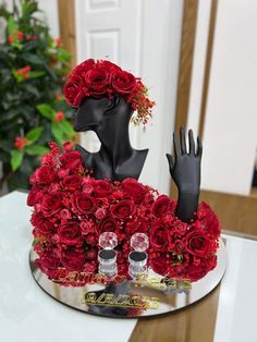 a vase filled with red roses on top of a table next to a pair of black gloves