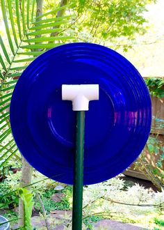 a blue frisbee that is on top of a green pole