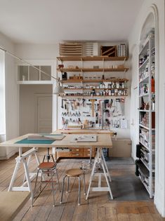 a room with several tables and chairs on the floor, shelves in the wall behind them