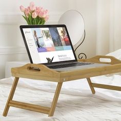 a laptop computer sitting on top of a wooden tray