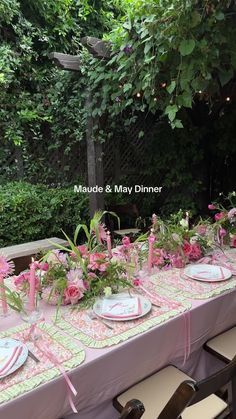 the table is set with pink flowers and place settings for an outdoor dinner or bridal party