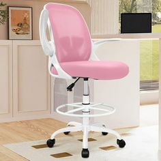 a pink and white office chair sitting on top of a wooden floor next to a window